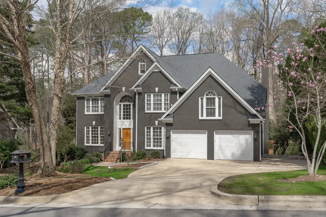The same brick colonial with the brick painted deep charcoal gray, white trim and a natural wood front door