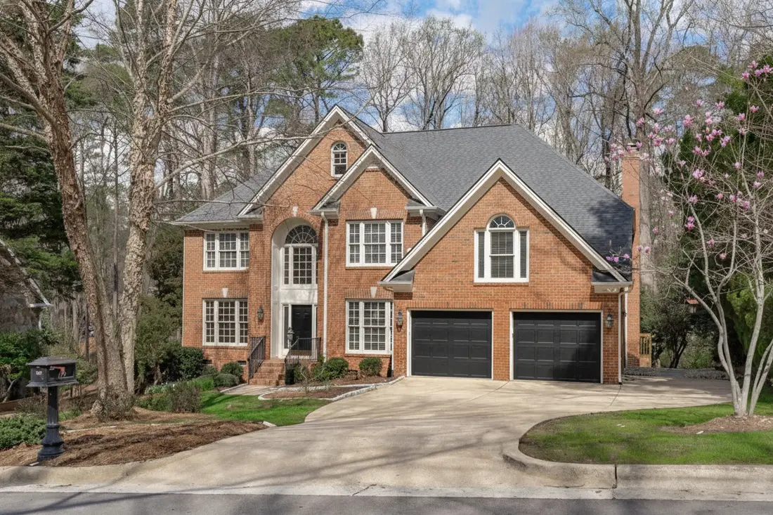 The same brick colonial with the red brick untouched and only the front door and both garage doors painted black
