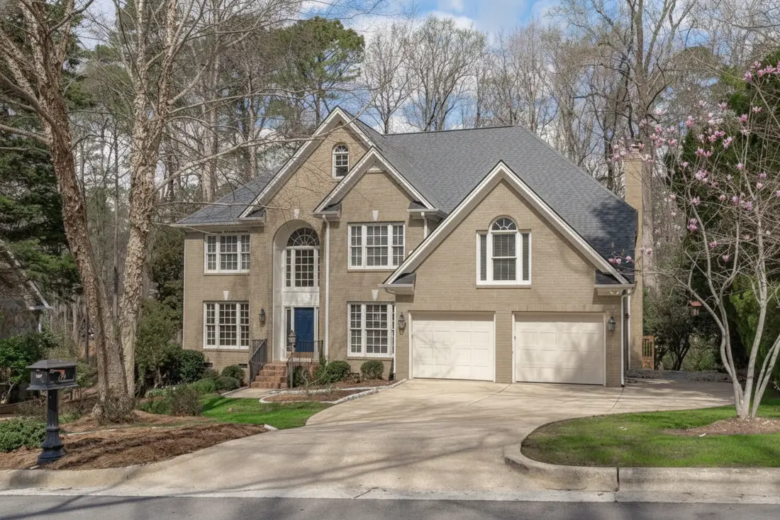 The same brick colonial with the brick painted soft warm greige, white trim and a deep navy front door