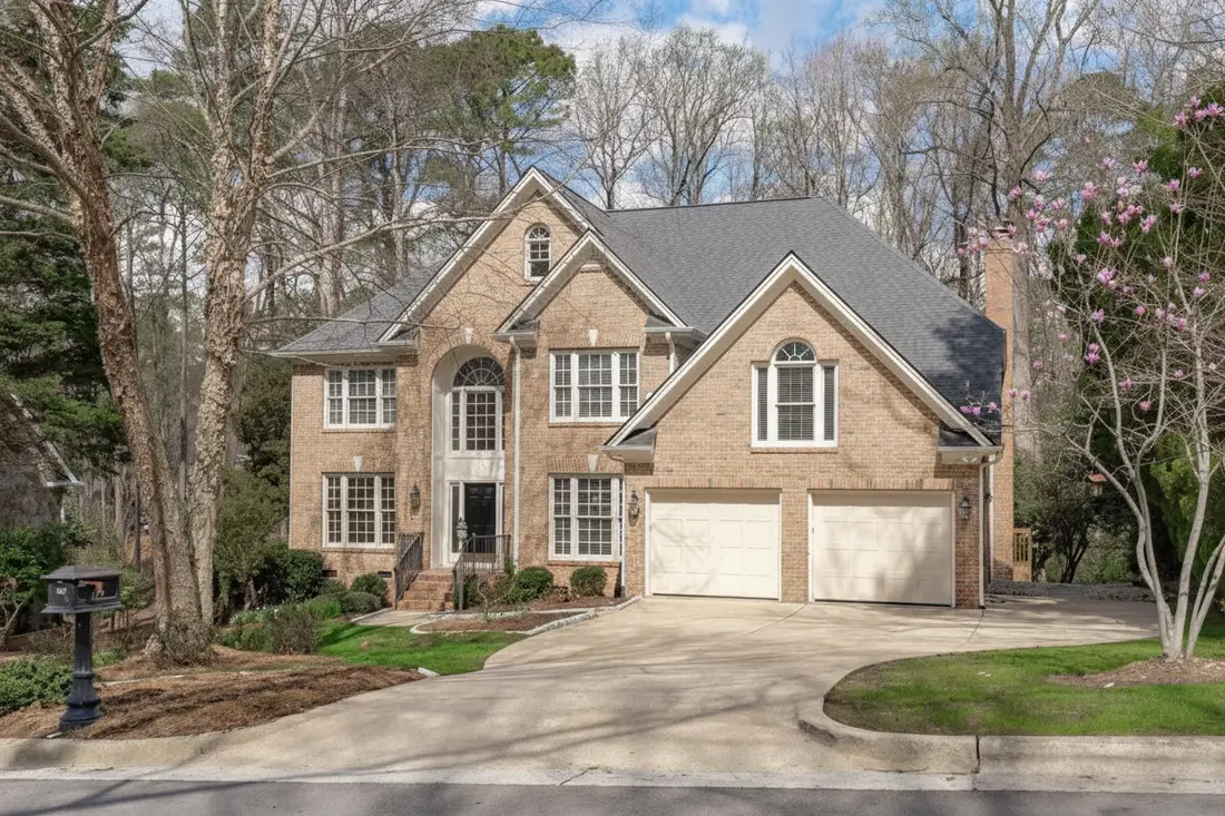 The same brick colonial with the brick lightened to a blonde limewashed tone rather than solid white