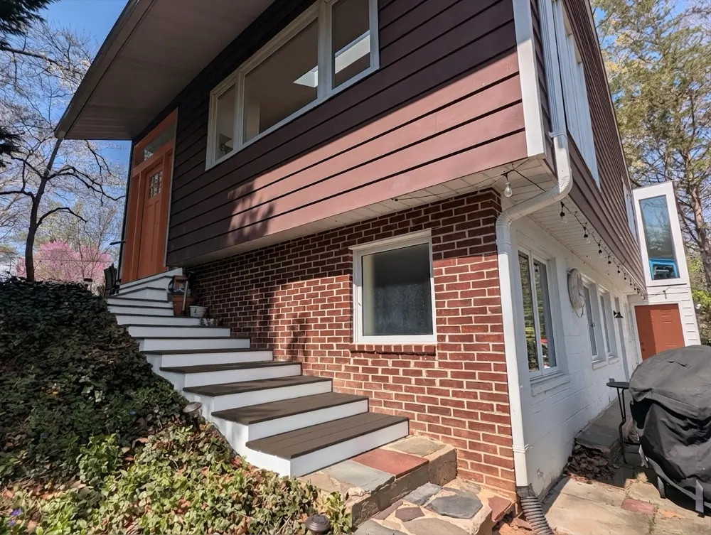 Rust front door tying warm red brick to chocolate brown siding on a mid-century split-level